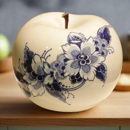 Witte decoratieve appel met blauw bloemmotief op houten tafel in keuken