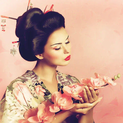 Portret van een Japanse geisha vrouw met traditioneel kapsel en kimono, houdend roze orchideeën vast