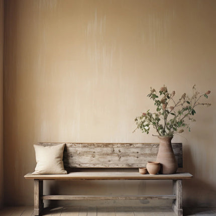 Rustieke houten bank met beige kussen en vazen met bloemen tegen een zandkleurige muur