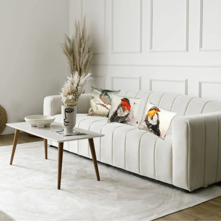 Wit modern interieur met fluwelen bank en sierkussens met vogelprint, witte salontafel met vaas