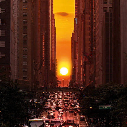 Drukke stadsstraat met verkeer bij zonsondergang tussen hoge gebouwen in New York